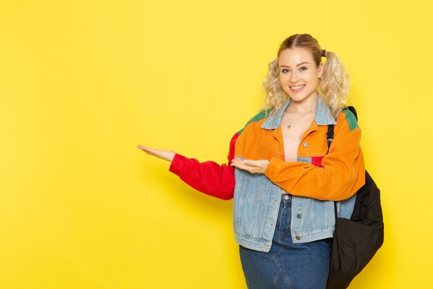 female student young in modern clothes just simply posing with smile on yellow