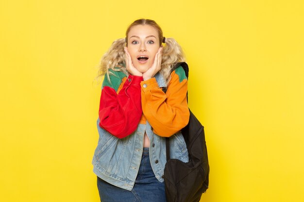 female student young in modern clothes just simply posing with surprised expression on yellow