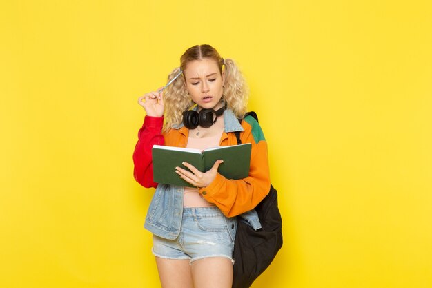 female student young in modern clothes reading copybook on yellow