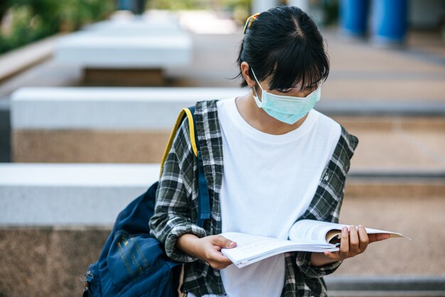 Female students wearing masks and books on the stairs.