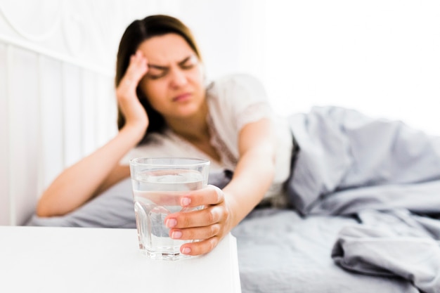 Female suffering from headache taking glass of water