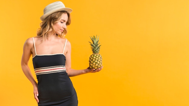 Female in summer clothes looking at pineapple