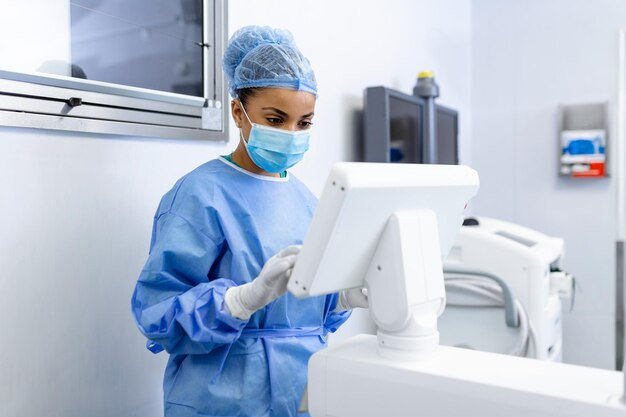 3d 이미지 유도 수술 기계를 사용하여 수술실에서 외과용 마스크를 쓴 여성 외과의사