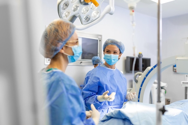 手術室でサージカルマスクを持った女性外科医病院の手術室で外科用制服を着た若い女性医師