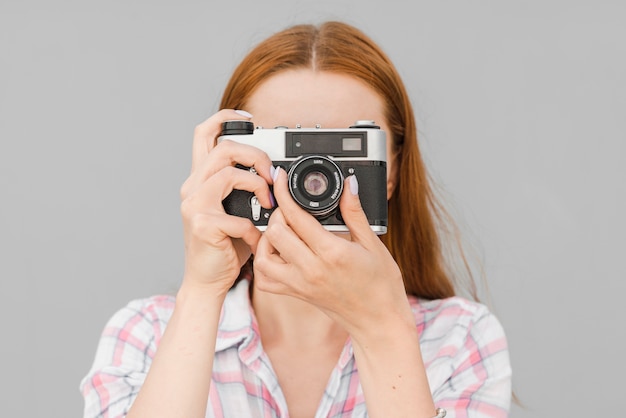 Female taking picture on old camera in studio