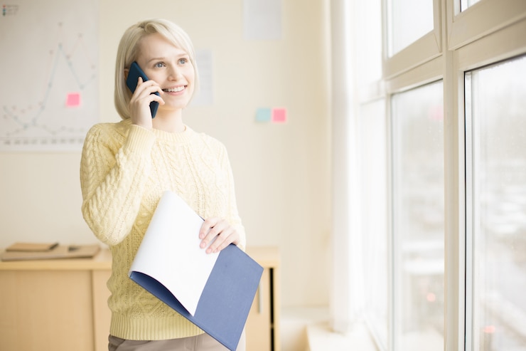 Free Photo female talking on mobile phone in office