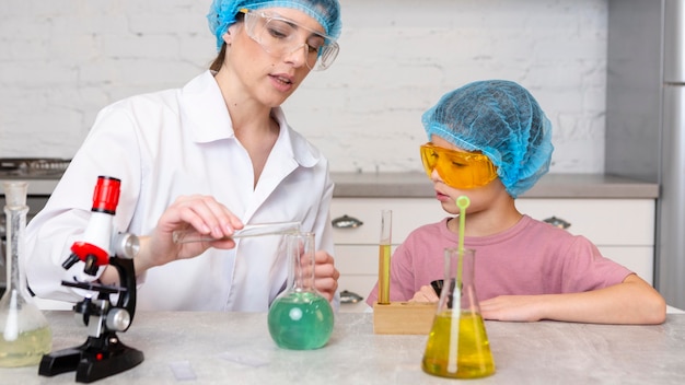 Female teacher and girl with hair nets doing science experiments with test tubes and microscope