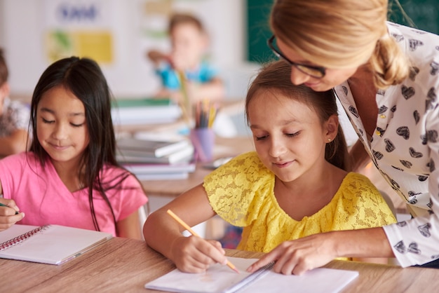 Female teacher helping kids in exercises