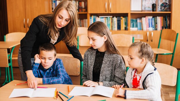 Female teacher helping pupils in studying process