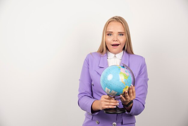 Female teacher holding globe with both hands.