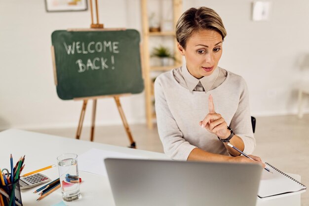 コンピューターでオンライン授業をしている女教師