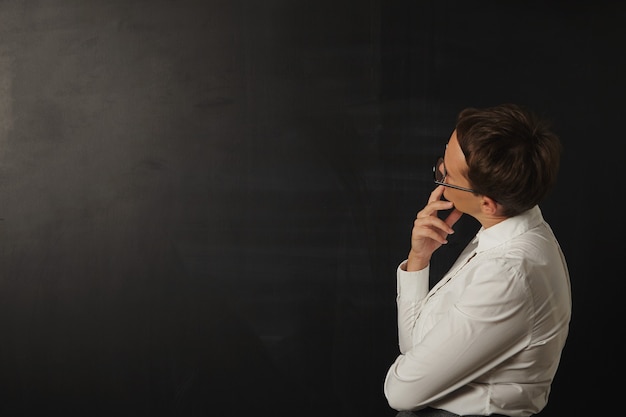 Free photo female teacher looking at an empty black blackboard