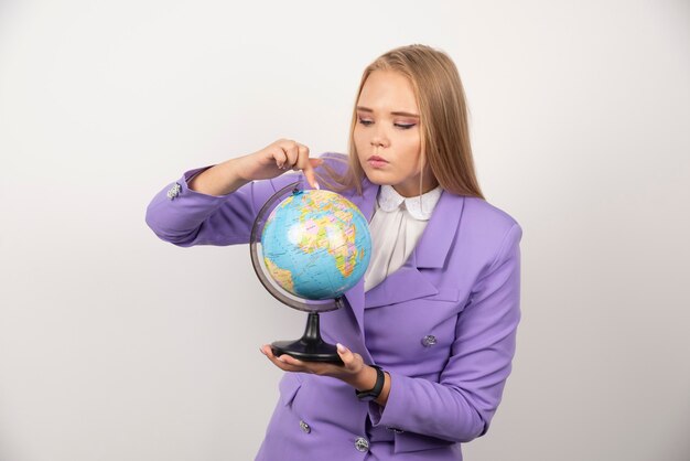 Female teacher looking at globe on white.
