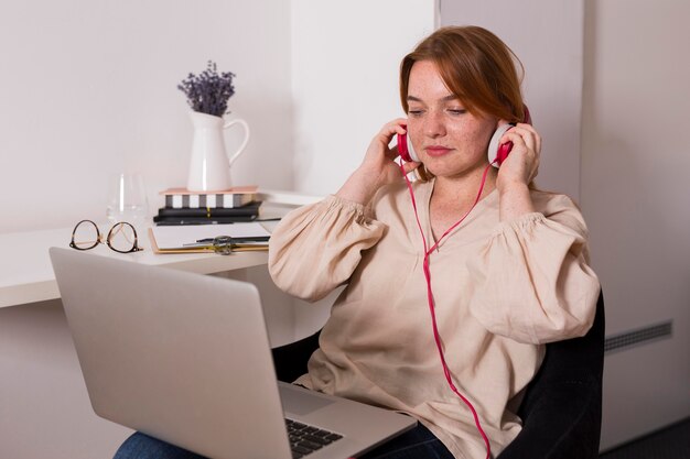 Female teacher putting on headphones at home for the online class