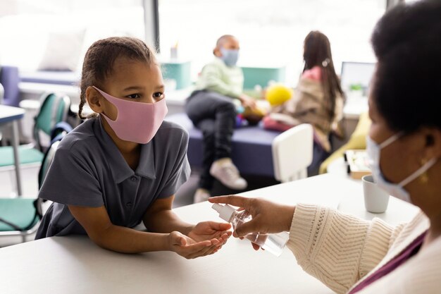 Female teacher teaching kids about disinfecting