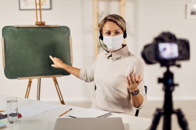 Female teacher with protective face mask recording lecture for eleaning during virus pandemic