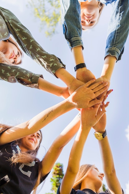 Female teen friends stacking hands together