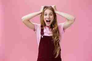 Free photo female teenager cannot calm down feeling excited going on favorite band concert holding hands on head screaming from amazement and surprise standing overreacting against pink background.