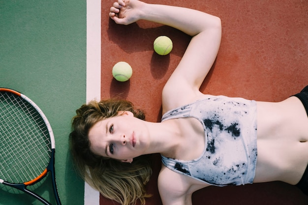 Female tennis player lying on ground and looking towards sky