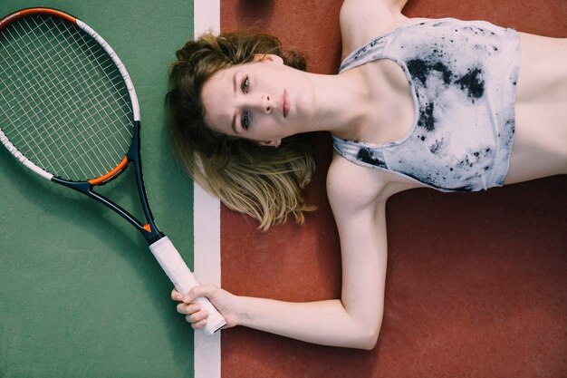 Женская теннисистка отдыхает на земле