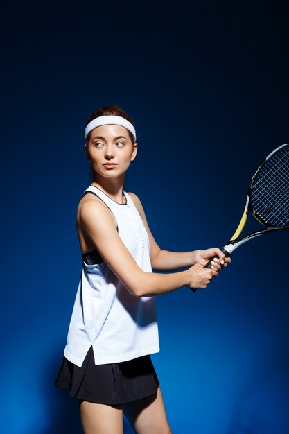 Female tennis player with racket ready to hit a ball.