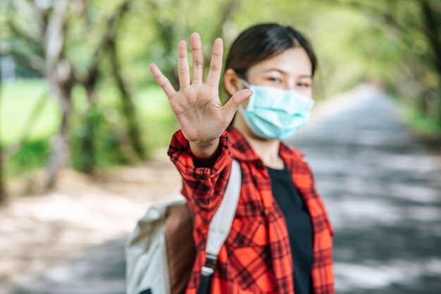 배낭을 들고 도로에서 금지하는 다섯 손가락을 올리는 여성 관광객.