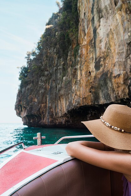 ボートに乗って傾いている女性観光客が崖の近く旅行します。