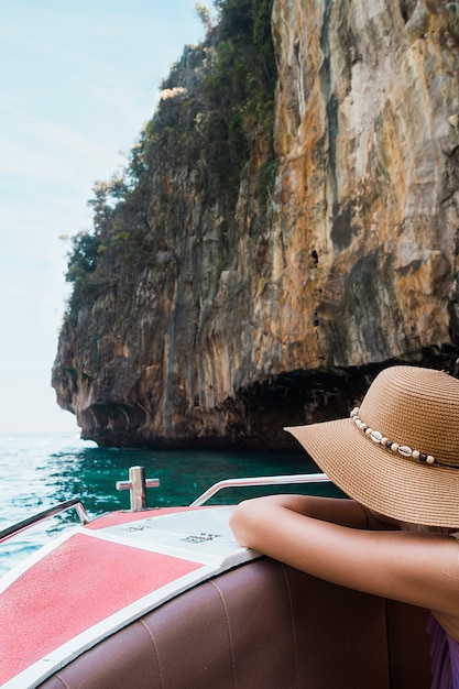 ボートに乗って傾いている女性観光客が崖の近く旅行します。