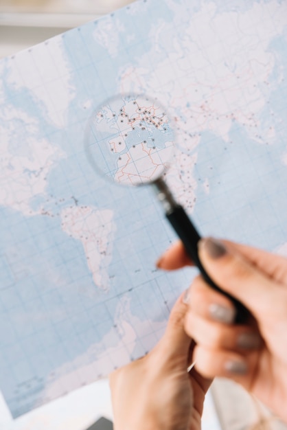 A female tourist searching places for travel on map through magnifying glass