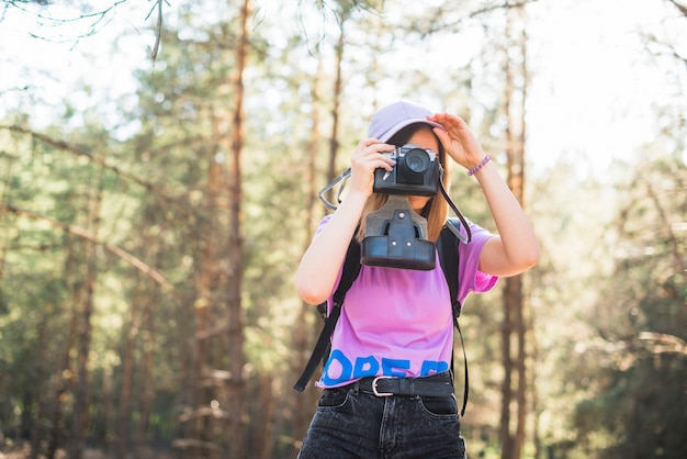 Женский турист фотографирует в лесу