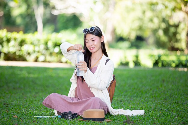 女性観光客は水を飲んでいます。