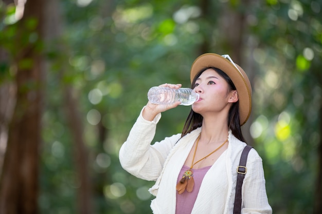 女性観光客は水を飲んでいます。