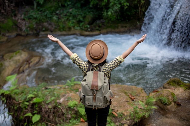 女性観光客は幸せで、滝でリフレッシュします。