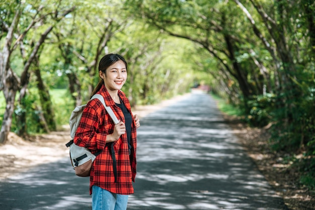 여성 관광객은 배낭을 들고 거리에 서 있습니다.