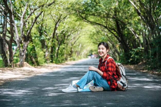 배낭을 들고 도로에 앉아 여성 관광객.