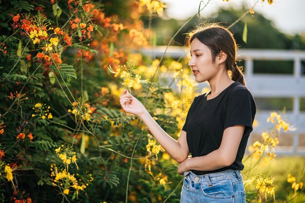 女性観光客が立ち、庭の花をキャッチします。