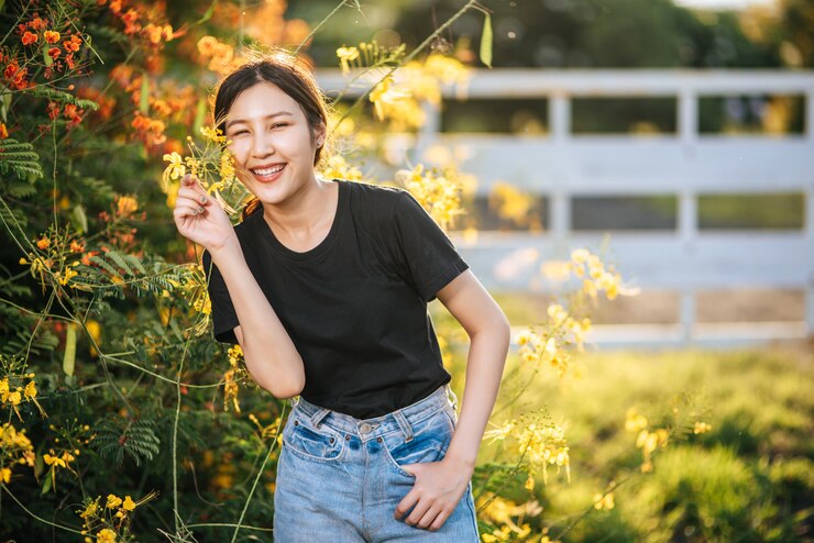 무료 Photo 여성 관광객이 서서 정원에서 꽃을 잡습니다.