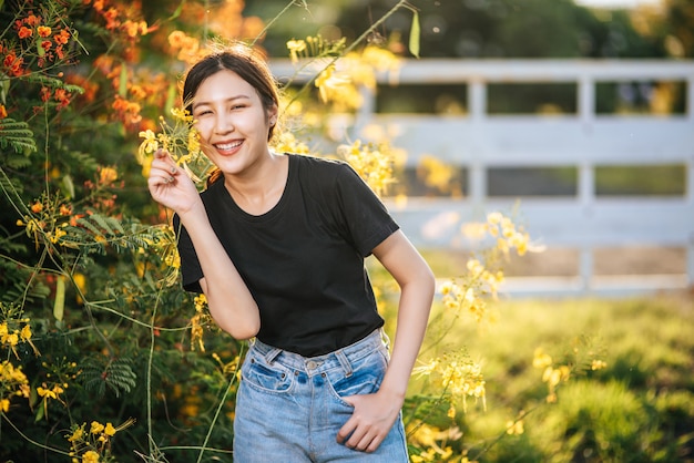 女性観光客が立ち、庭の花をキャッチします。