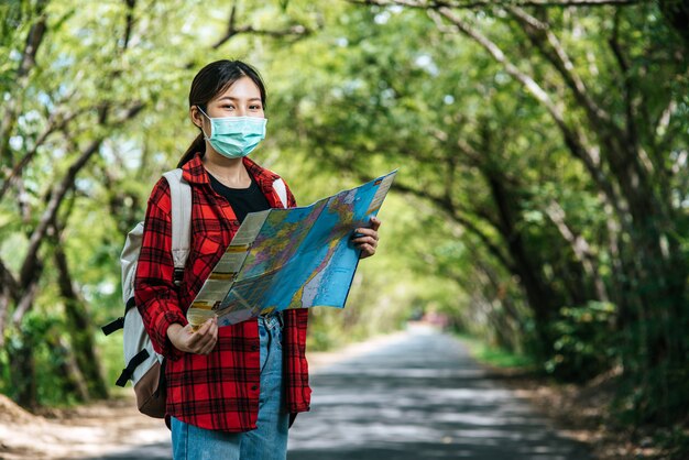 Female tourists stand and look at the map on the road.