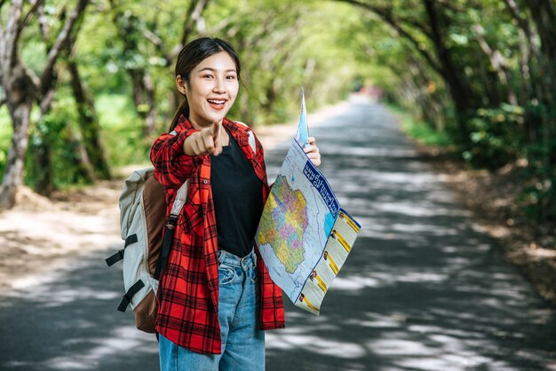 女性観光客が立ち、道路上の地図を見る。