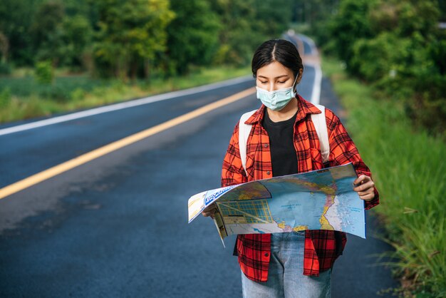 Женщины-туристы стоят и смотрят на карту на дороге.