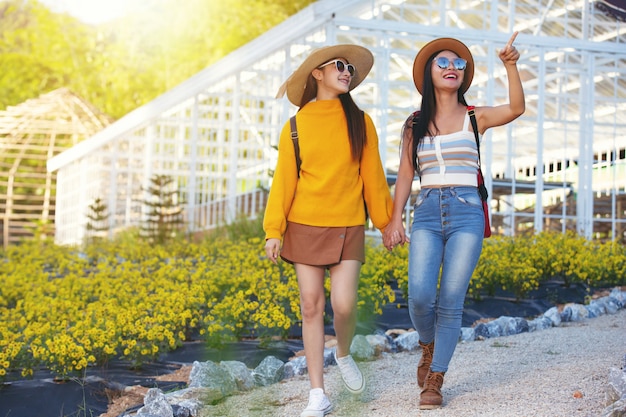 Female tourists walk holding arms 