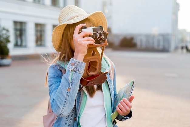 Женский путешественник, держа карту в руке, принимая изображение с камеры на улице города