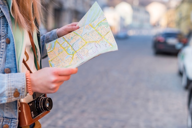 Female traveler searching direction on location map in city center