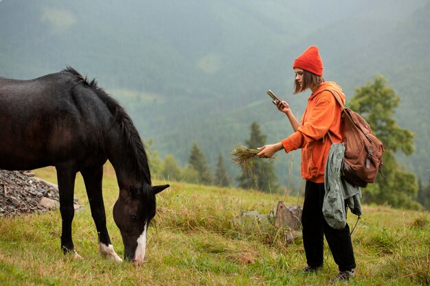 Female traveler trying to feed a horse