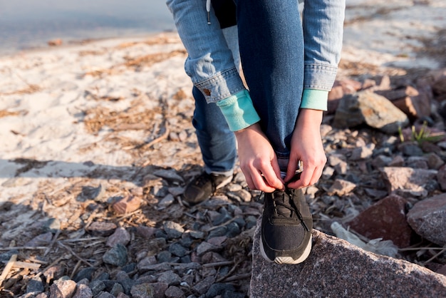 Free photo female traveler tying the shoelace on beach