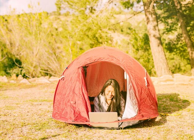 女性旅行者のキャンプでノートパソコンでの作業