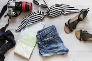 Free photo female travelling outfits with camera and map on desk