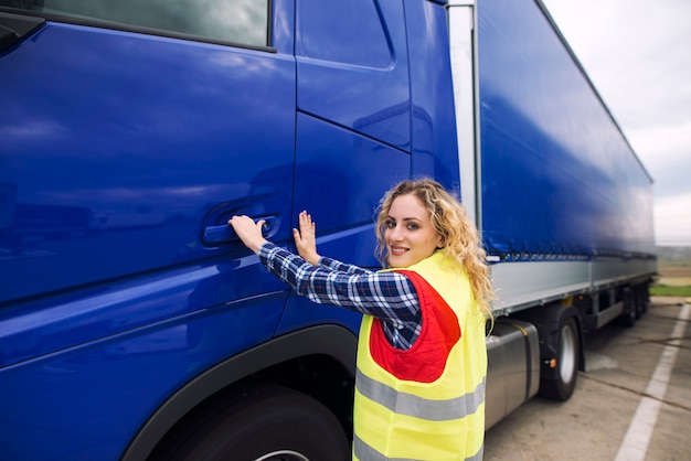 Female truck driver opening cabin door and entering truck vehicle