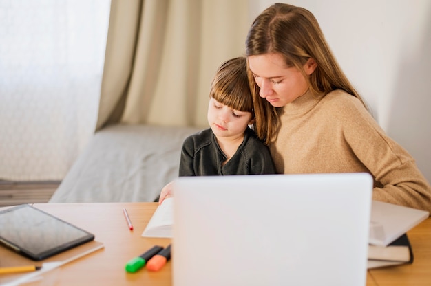 Female tutor teaching child at home with laptop